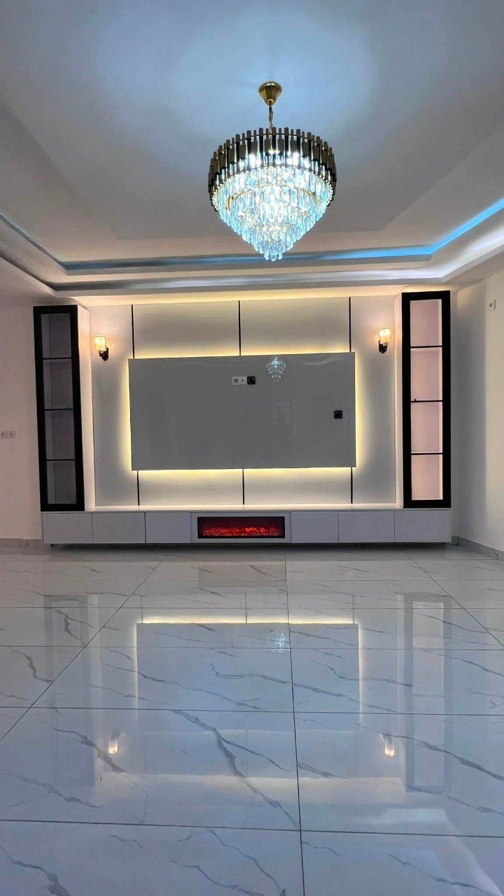 Salon fini avec lustre en cristal, mur TV rétroéclairé et cheminée décorative