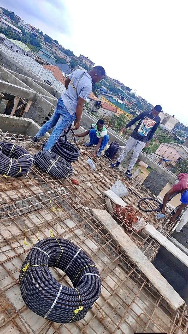 Équipe posant des gaines électriques sur le ferraillage d'une toiture-terrasse en construction