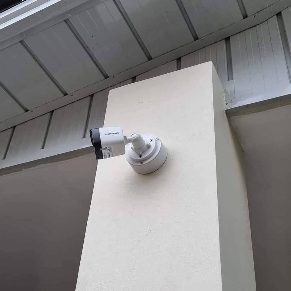 Caméra de vidéosurveillance extérieure fixée sur un pilier technique sous auvent