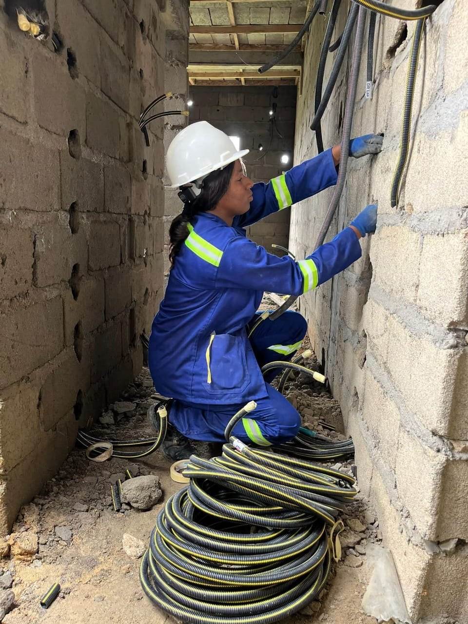 Technicienne tirant des gaines électriques dans une cage d'escalier en construction