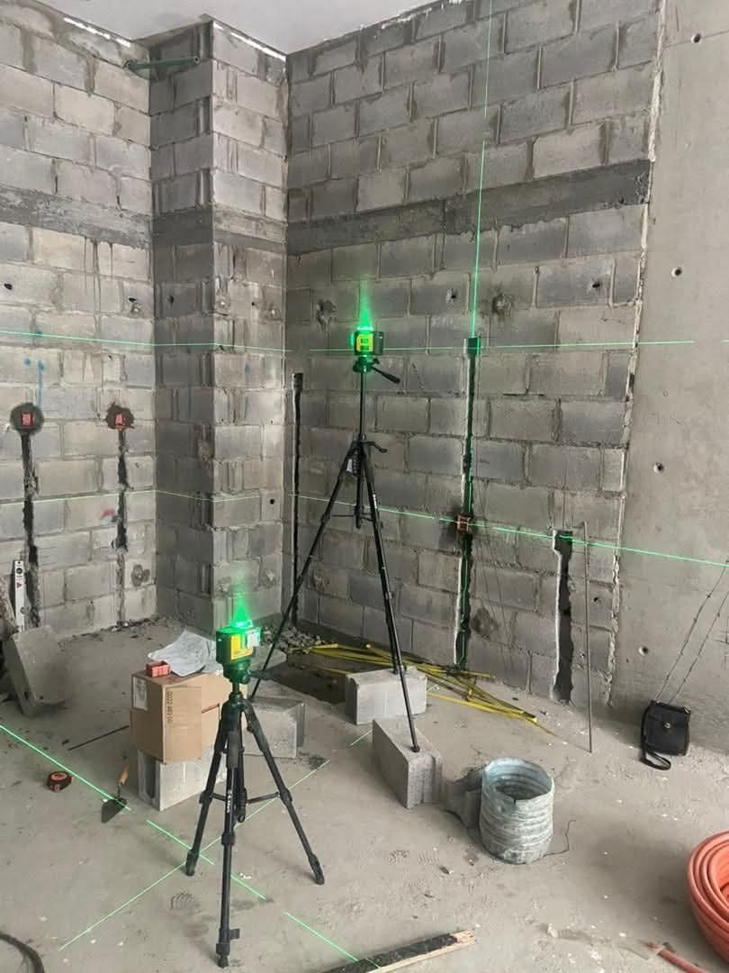 Deux niveaux laser sur trépied reportant des repères dans une pièce en chantier